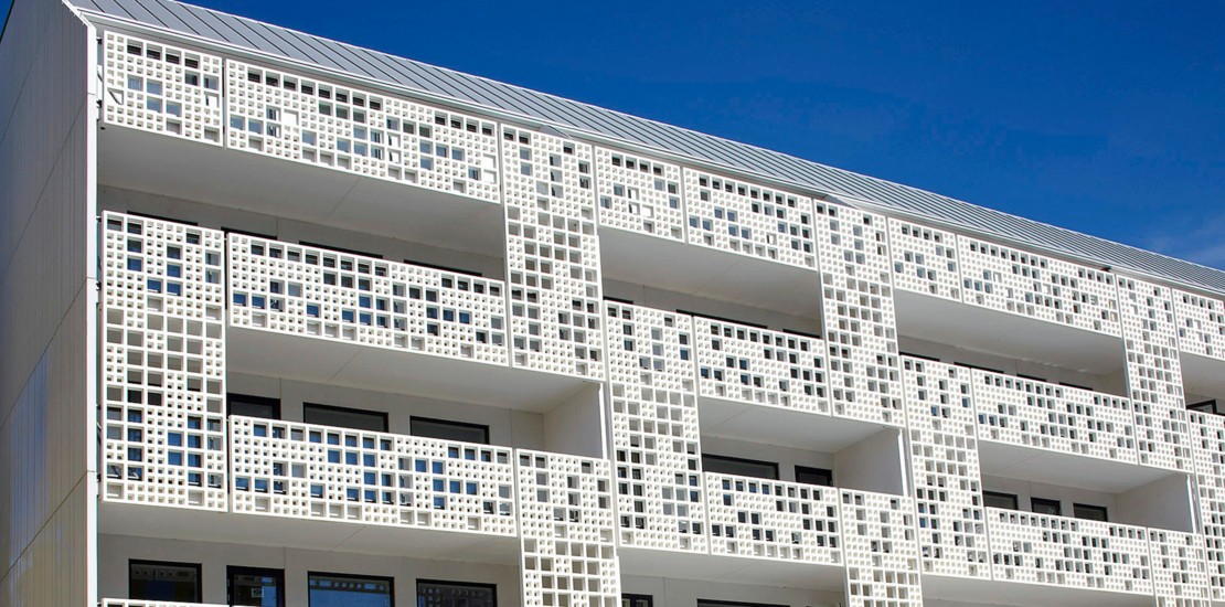 Die vorgelagerte Fassade aus strahlendem Weiß dient als raffinierter Sichtschutz und bietet durch die Perforierung eine hohe Transparenz.