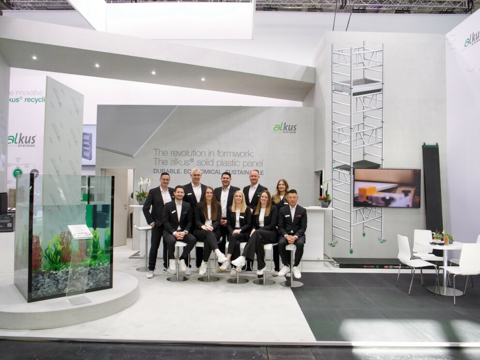 Das alkus Team mit dem neuen Geschäftsführer Daniel Keller und Inhaber Julian Dingler (2. Reihe, 3. und 4. v. l.) vor dem Messestand der alkus AG, links das Aquarium. The alkus team with the new Managing Director Daniel Keller and owner Julian Dingler (2nd row, 3rd and 4th from left) in front of the alkus AG stand, with the aquarium on the left. | © alkus AG / Jens Ellensohn